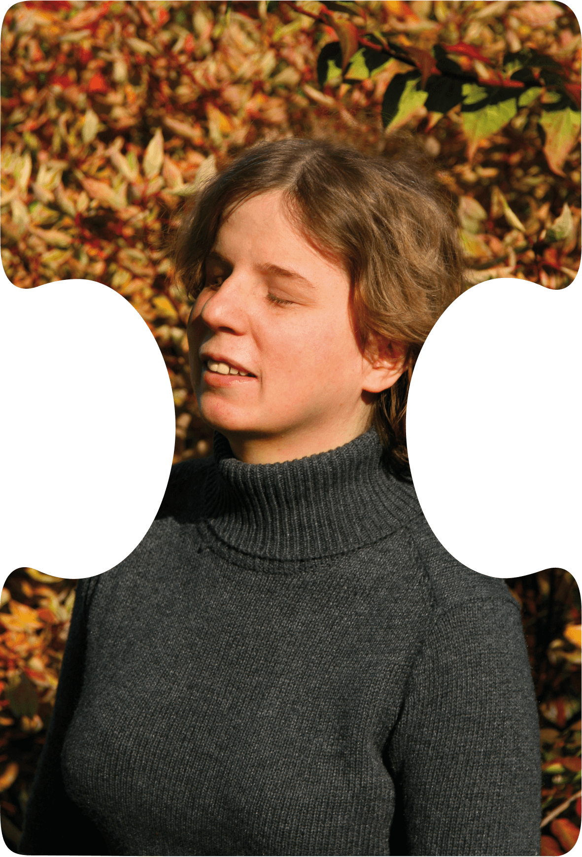 Bianka steht vor herbstlichem Hintergrund und schaut lächelnd nach links.